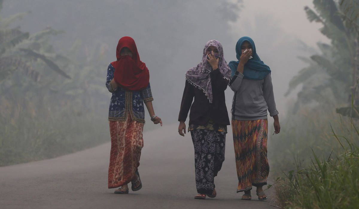 Villagers walk on a street in Muaro Jambi
